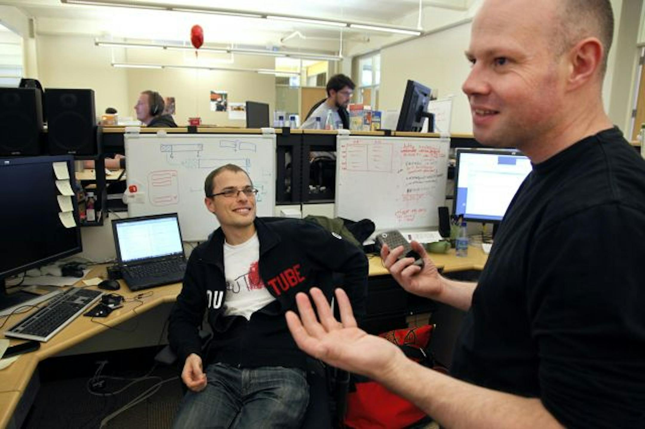 YouTube Web developer Toby Watson, right, discusses smart phones with software engineer Simon Ratner at the YouTube office in San Bruno, Calif.
