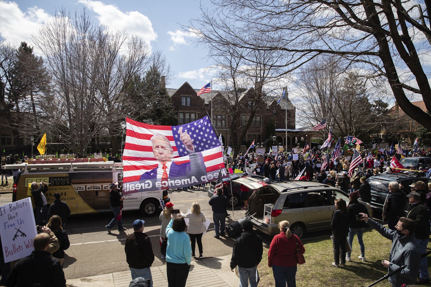 FILE - In this April 17, 2020, file photo a giant banner depicting President Trump is flown in front of the Governor's residence during a "Liberate Minnesota" protest in St. Paul, Minn. Heading into the weekend, President Donald Trump actively encouraged people to protest stay-at-home orders in a handful of battleground states led by Democratic governors. (Evan Frost/Minnesota Public Radio via AP, File)