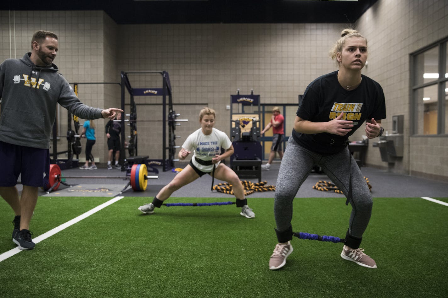 Waconia strength and conditioning coach Josh Anderson, left, coached soccer player Devin Breeggemann and basketball player Courtney Freeberg, right, in a warm-up that included a lateral band walk.