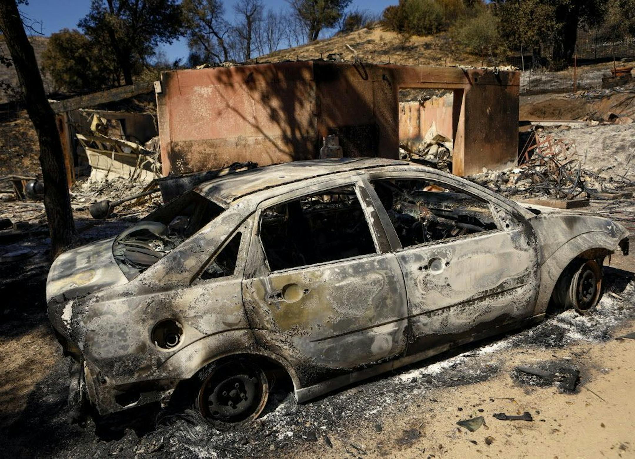 A burned out car sits next to a destroyed home after a wildfire in Santa Margarita, Calif., Wednesday, June 28, 2017. (Joe Johnston/The Tribune
