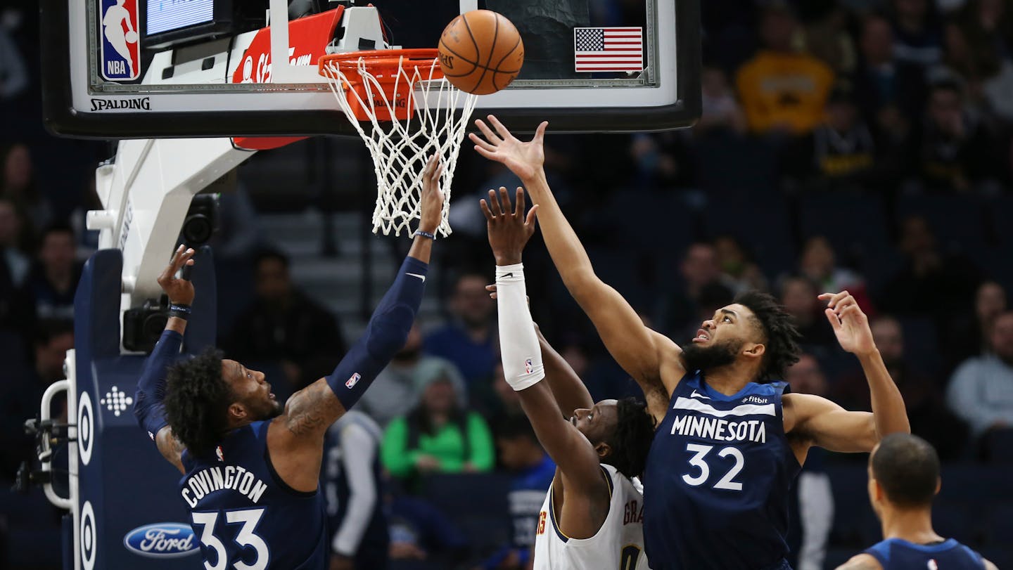 The Timberwolves' Karl-Anthony Towns reaches up to rebound the ball over Denver's Torrey Craig