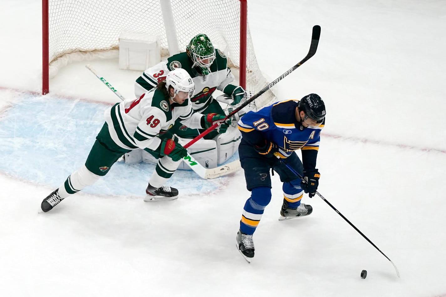 St. Louis Blues' Brayden Schenn (10) controls the puck as Minnesota Wild goaltender Kaapo Kahkonen (34) and Victor Rask (49) defend during the first period of an NHL hockey game Friday, April 9, 2021, in St. Louis. (AP Photo/Jeff Roberson)