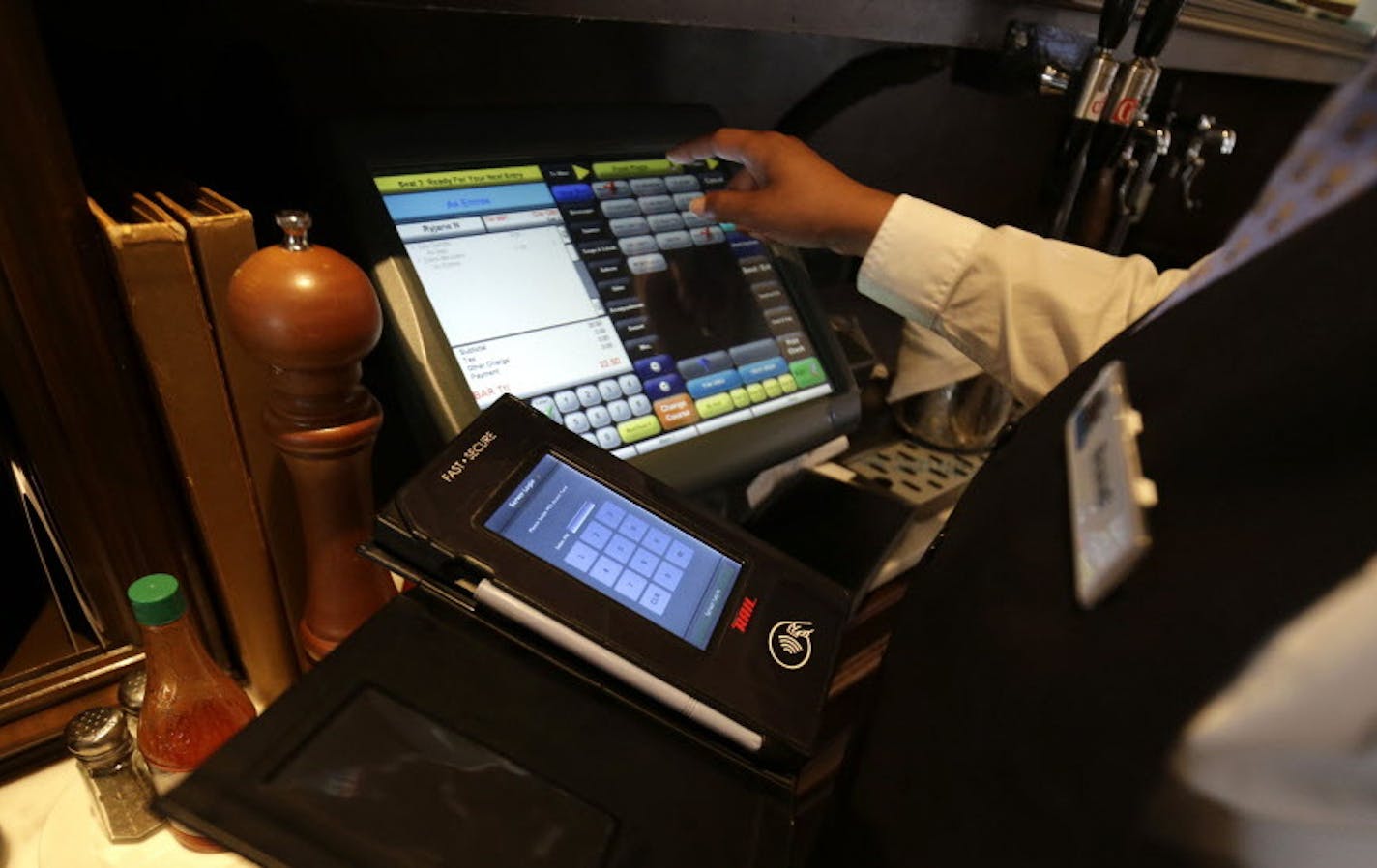 Waitress Courtney Jones processes a dinner tab with a Rail table side credit card processing device at Tableau, a Dickie Brennan & Co. restaurant, in New Orleans, Monday, June 15, 2015. Dickie Brennan & Co., which operates four New Orleans restaurants, expects to pay more than $25,000 to replace card readers and software once chip cards are phased in and magnetic stripe cards, which are easier for thieves to copy, are phased out. (AP Photo/Gerald Herbert)