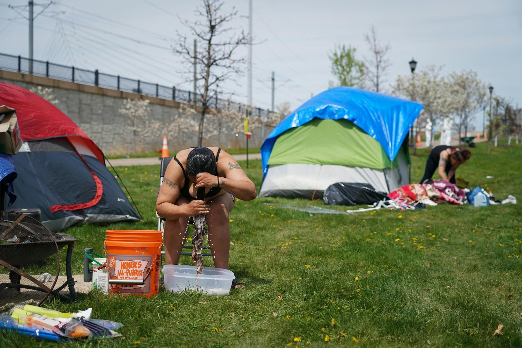 Jennifer Hernandez used non-potable water brought to a homeless camp along Hiawatha to wash her hair outside her tent.