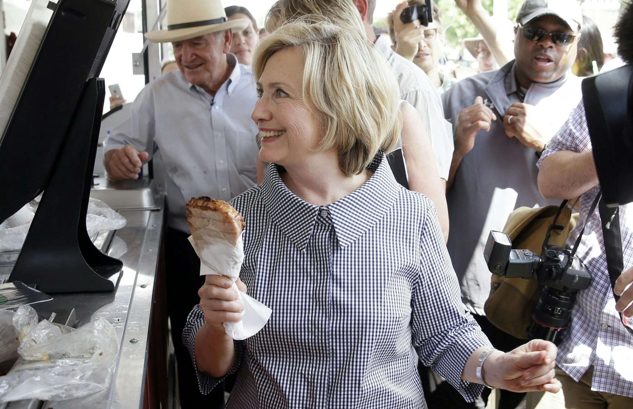Democratic presidential candidate Hillary Rodham Clinton buys a pork chop during a visit to the Iowa State Fair, Saturday, Aug. 15, 2015, in Des Moines, Iowa. (AP Photo/Charlie Neibergall)