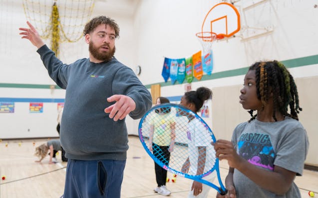 Tennis professional Anthony King teaches the proper technique of an overhead swing to Zion Rootues during an InnerCity Tennis-led physical education c