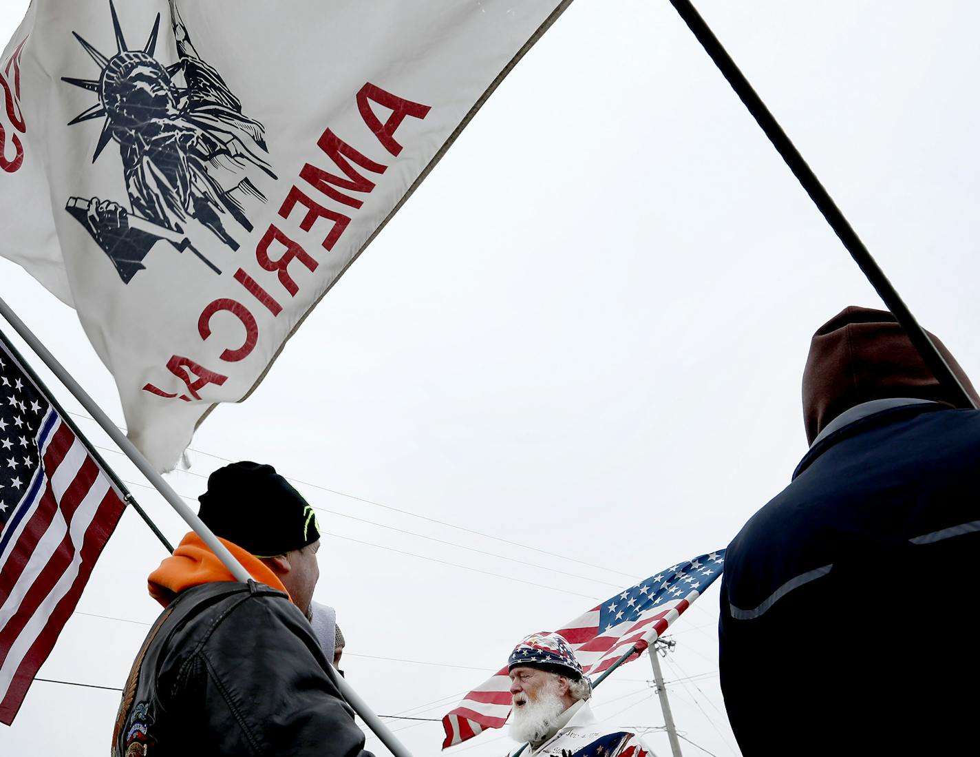 Advocates Steve Berg of Belle Plaine, Katie Novotny of Belle Plaine, Red Bartholomew of Crystal and Rex Ernst of Belle Plaine guarded a cross at the veterans memorial park in Belle Plaine, MN on Tuesday. ] CARLOS GONZALEZ cgonzalez@startribune.com - January 24, 2017, Belle Plaine, MN, A group of flag-toting Belle Plaine residents has taken it upon themselves to keep guard over the small town's veteran's memorial, rebelling against city's decision to remove a cross from a fallen soldier's grave m