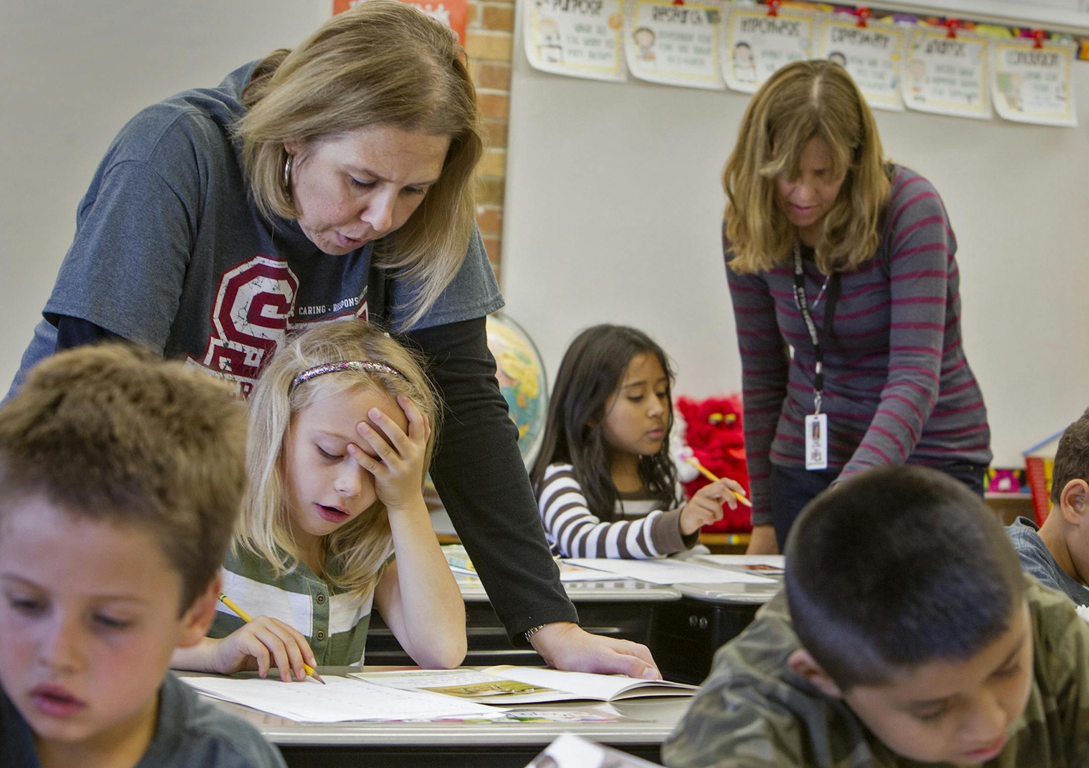 Classroom teacher Stacy Krohn, left, helps second-grader Maya Burns with a science content writing exercise as ESL teacher Anne Hillman, standing right, helps ELL student Monika Pichardo in Krohn's second and third grade split classroom at Sheridan Hills Elementary School in Richfield October 25, 2013. (Courtney Perry/Special to the Star Tribune) ORG XMIT: MIN1310251605222727