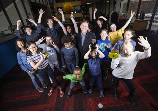 Children's Theatre artistic director Peter Brosius posed for a picture with a group of children, some holding his Ivy and Tony awards, who are part of