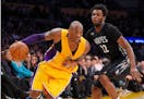 Los Angeles Lakers forward Kobe Bryant, left, drives past Minnesota Timberwolves guard Andrew Wiggins during the second half of an NBA basketball game