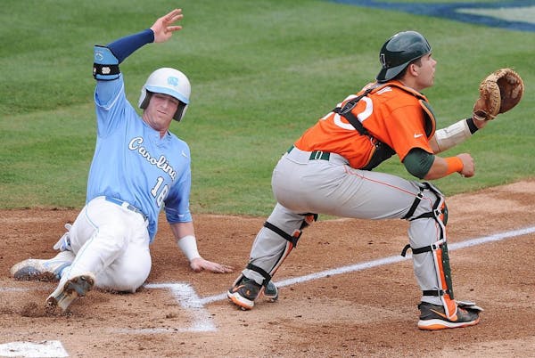 North Carolina's Colin Moran slides safely home as Miami catcher Garrett Kennedy waits for the late throw during the Atlantic Coast Conference champio