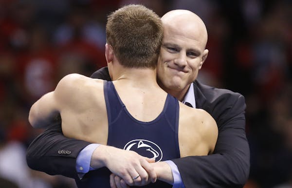 Penn State coach Cael Sanderson, right, hugs David Taylor, left, after Taylor defeated Oklahoma State's Tyler Caldwell in the 165-pound match in the f