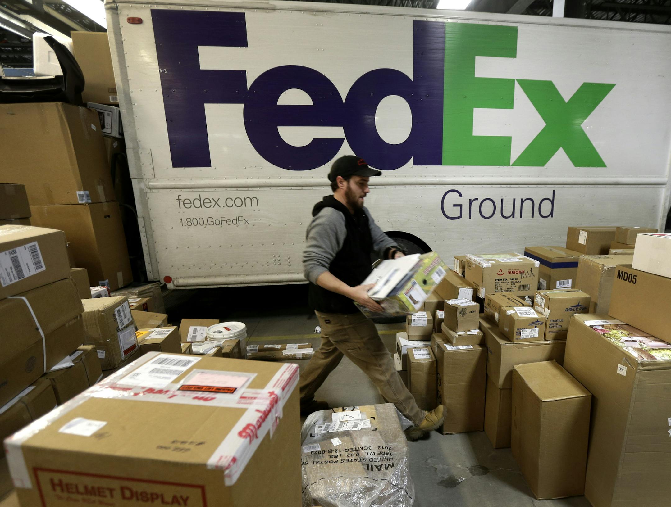 FILE - In this Dec. 16, 2013 file photo, package handler Chris Addison arranges packages before loading a delivery truck at a FedEx sorting facility in Kansas City, Mo. Santa's sleigh didn't make it in time for Christmas for some this year due to shipping problems at UPS and FedEx.The delays were blamed on poor weather earlier this week in parts of the country as well as overloaded systems. (AP Photo/Charlie Riedel)