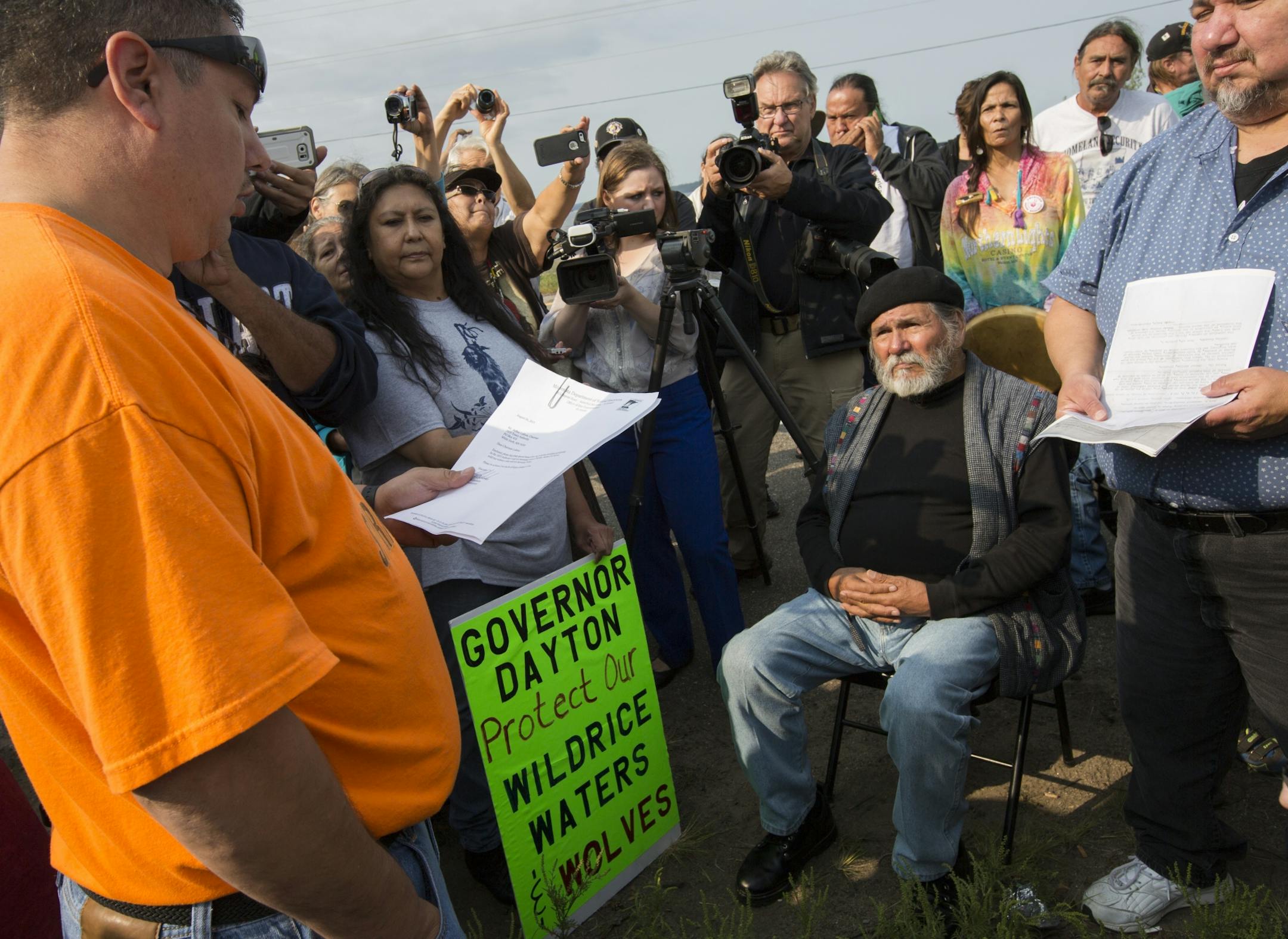 Arthur LaRose, Secretary Treasurer of Leach Lake Band of Ojibwa and Chairman of the 1855 Treaty Authority, (left) reads over the one day use permit issued by the DNR. Dennis Banks, (seated), co-founder of the American Indian Movement listens with other members of the tribe.