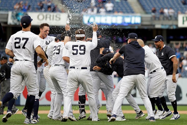 Teammates mob New York Yankees' Gary Sanchez after he hit a walkoff single against the Minnesota Twins during the 10th inning of a baseball game on Mo