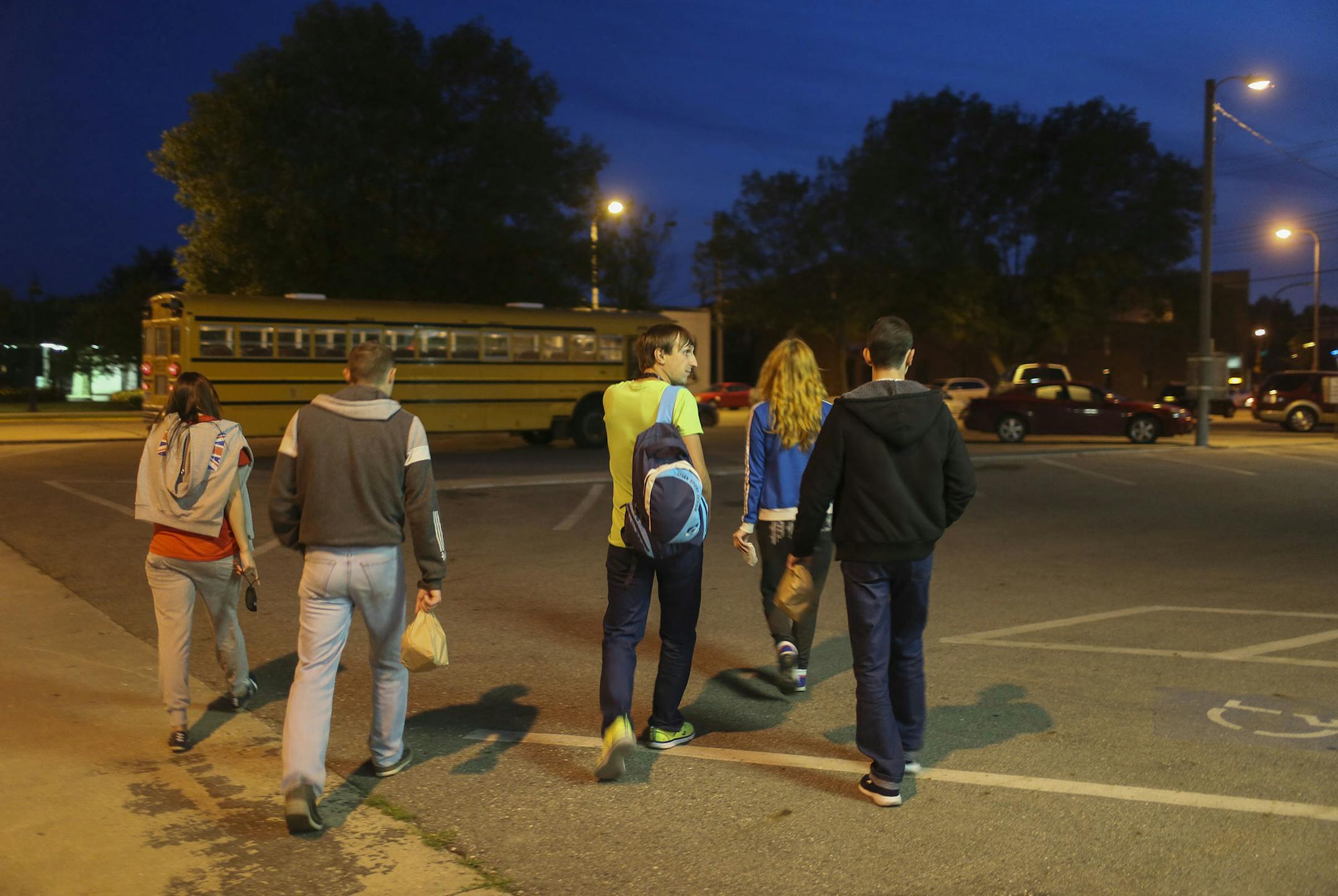 A group of mostly Ukrainian workers have come to Perham this summer for employment at KLN Enterprises, the family-owned parent company of Barrel O' Fun that also manufactures snack brands for other companies. Here, after eating a late dinner at the Wadena VFW, workers head to a school bus for the half hour ride that will take them to the temp jobs at KLN in Perham for the 11 p.m. shift Wednesday, July 16, 2014, in Wadena, MN.] (DAVID JOLES/STARTRIBUNE) djoles@startribune More than 60 internation