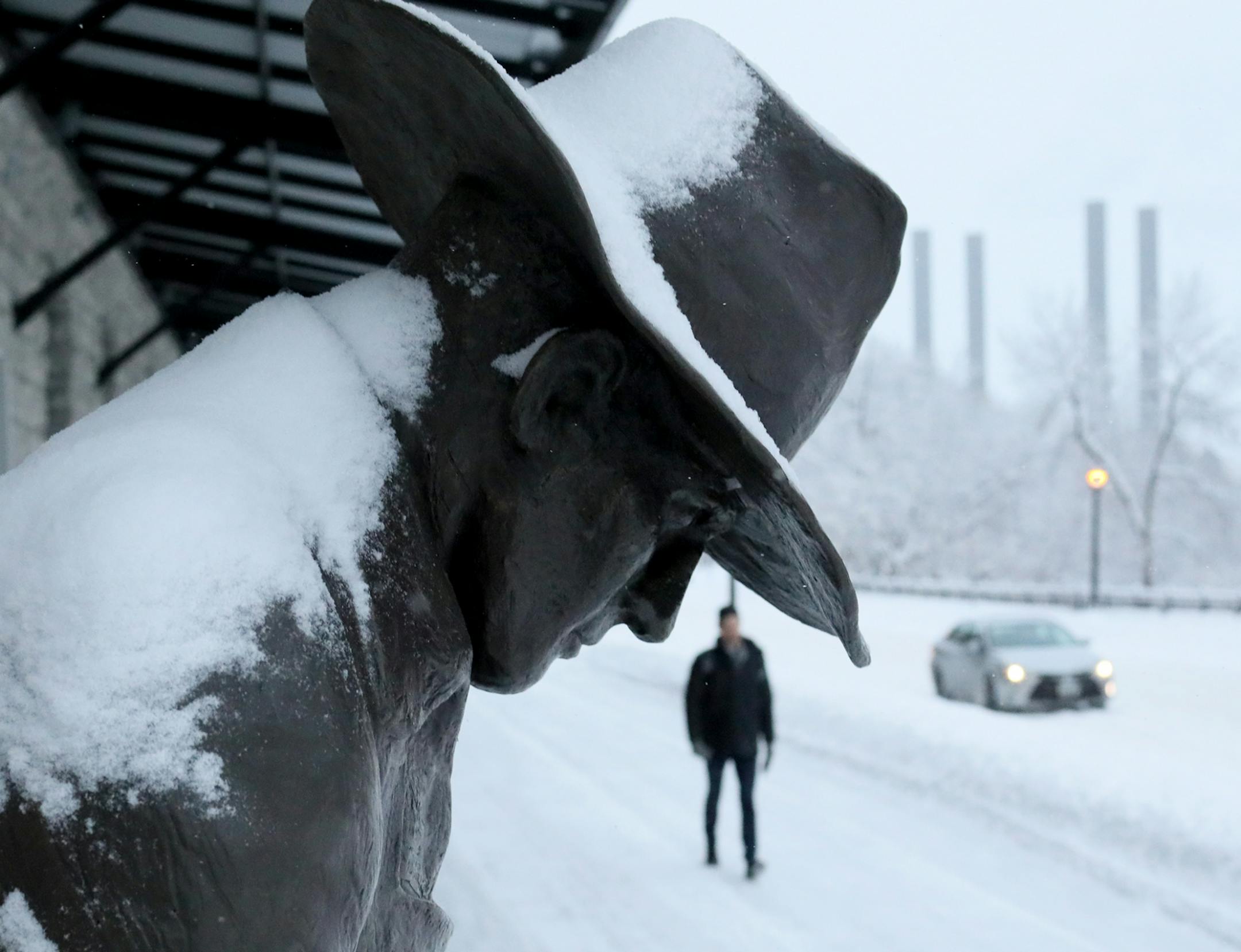 The latest round of fresh snow accumulates atop the sculpture "Man Lifting Wheat Sack," by artist Gary Ernest Smith at the corner of SE 3rd Ave. and SE First St. Tuesday, Feb. 12, 2019, in Minneapolis.
