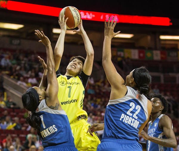 Seattle Storm's Ramu Tokashiki tries to muscle her way into the lane to shootver Minnesota's Jia Perkins (7) and Pienette Pierson (22) in the first ha