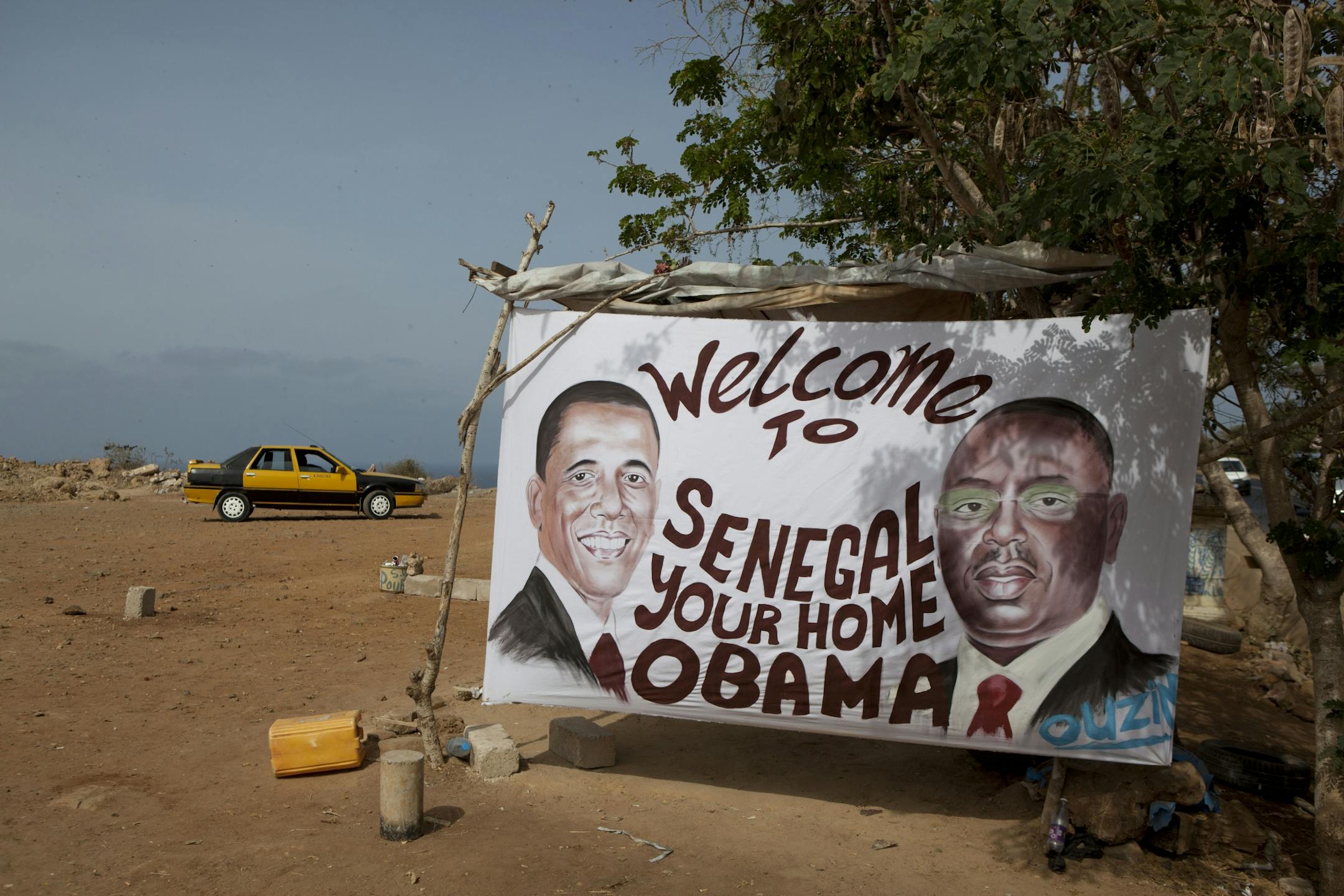 A painted banner depicting U.S. President Barack Obama and Senegalese President Macky Sall hangs along the roadside at the workshop of artist Ouzin, in Dakar, Senegal, Wednesday, June 26, 2013. The U.S. President and his family arrive in Senegal Wednesday night to kick off a three-country African tour.
