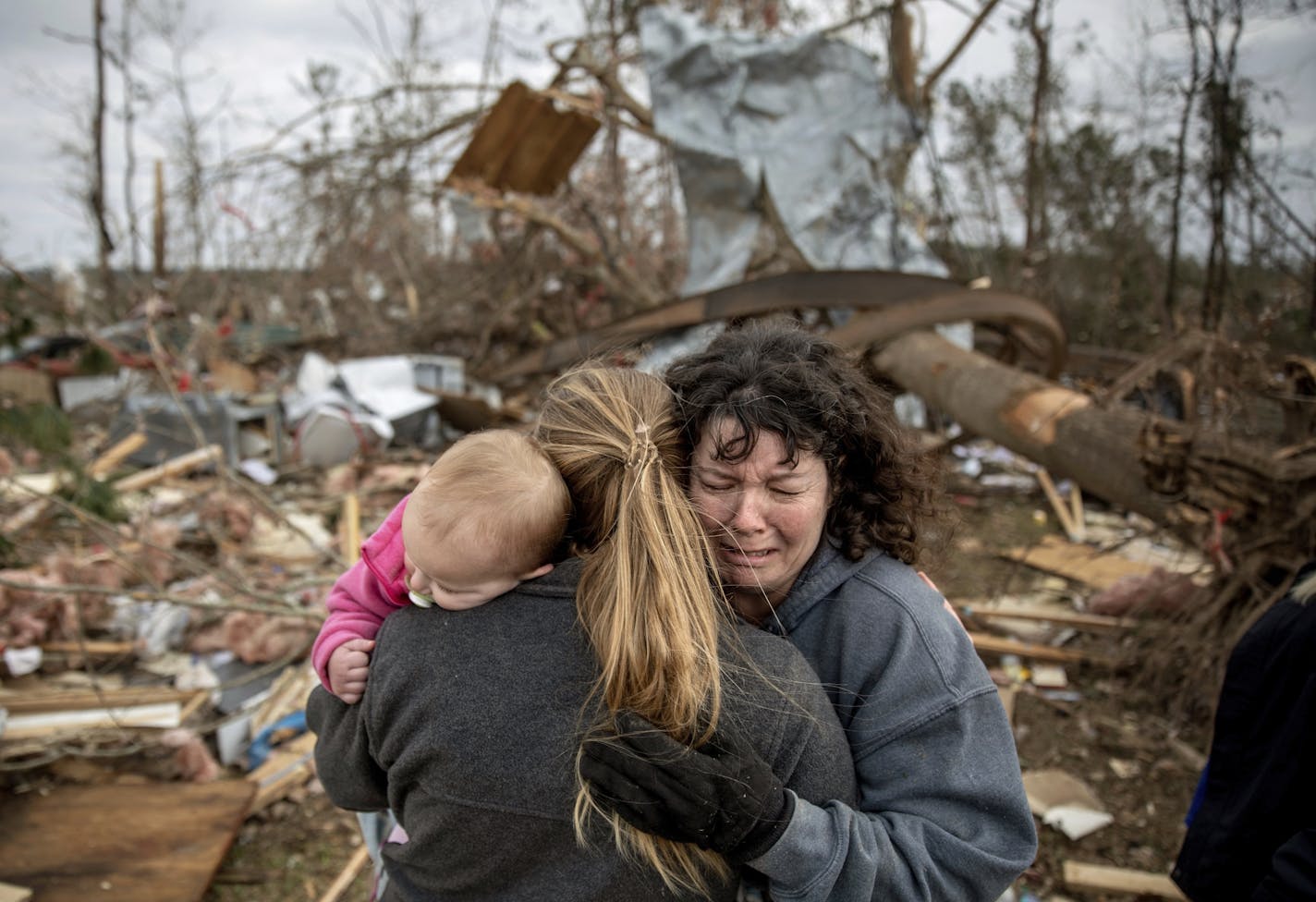 Carol Dean, right, cries while embraced by Megan Anderson and her 18-month-old daughter Madilyn, as Dean sifts through the debris of the home she shared with her husband, David Wayne Dean, who died when a tornado destroyed the house in Beauregard, Ala., Monday, March 4, 2019. "He was my wedding gift," said Dean of her husband whom she married three years ago. "He was one in a million. He'd send me flowers to work just to let me know he loved me. He's send me some of the biggest strawberries in t