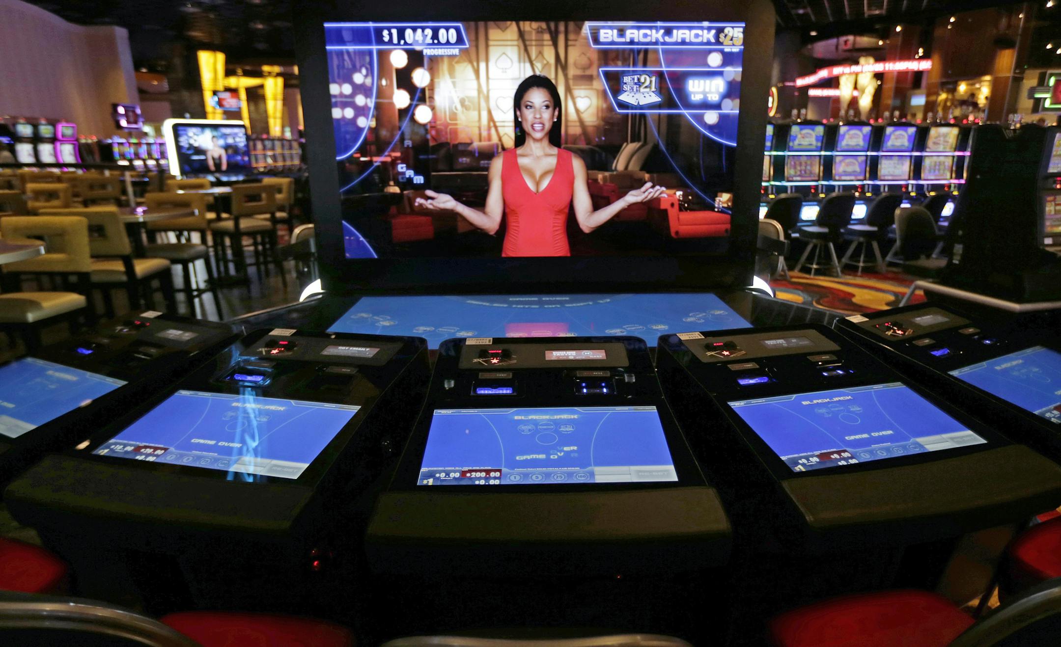 FILE - In this June 23, 2015, file photograph, an automated dealer asks for players to take a seat at a black jack video slot machine on the floor of the Plainridge Park Casino in Plainville, Mass. At the state's only casino, revenues were down in August, at about $15 million in gross gambling revenues, after posting about $18 million during July. (AP Photo/Charles Krupa, File)