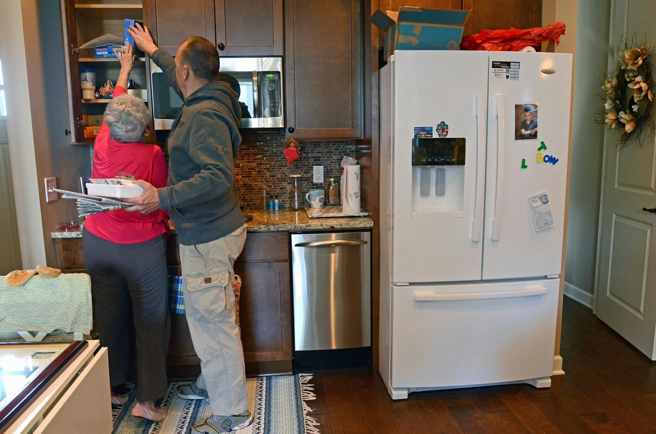 Karen Hokanson got some help from her son, Troy Hokanson, to reach an upper cupboard shelf in her apartment.
