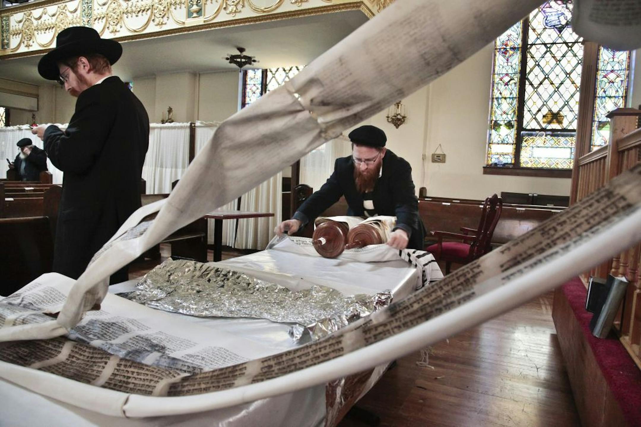 Rabbi Avremel Okonov, left, make calls to find a temporary location for a school, while his brother Rabbi Dovid Okonov rolls a water-damaged Torah, one of six damaged in floods from Superstorm Sandy, on Thursday, Nov. 1, 2012 at the Friends of Refugees of Eastern Europe (FREE) of Brighton Beach synagogue and community center in the Brooklyn borough of New York. A school at the center was flooded leaving 140 students from grades 1- 6 their school and Rabbi Avremel, its director, scrambling to fin