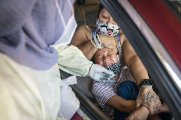 Jessica Steele of St. Paul held her son Little Bear Chatman, Jr., 6, as he was tested at North Memorial Health in Robbinsdale. The facility tested a t