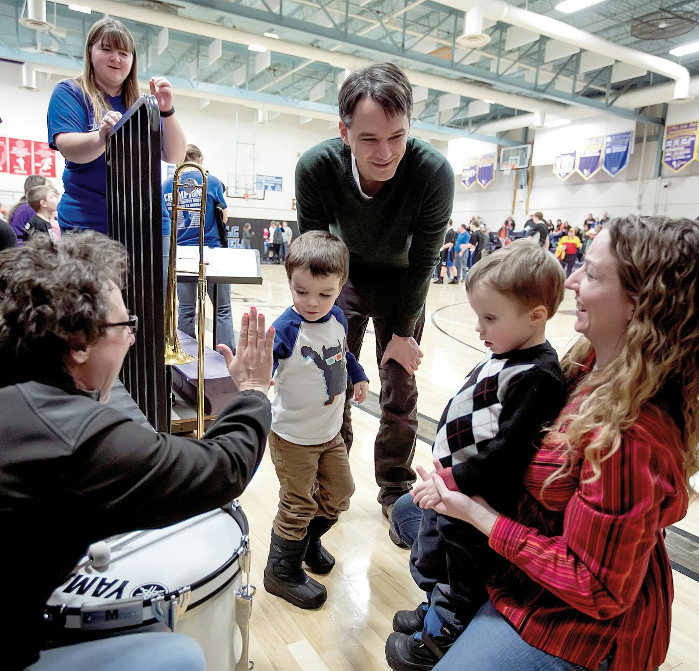 The Ingraham boys (Jack and Charlie) get a high five from Mindy Pierson after checking out the drums in the pep band during a Red Lake Falls High School basketball game on a Friday night.