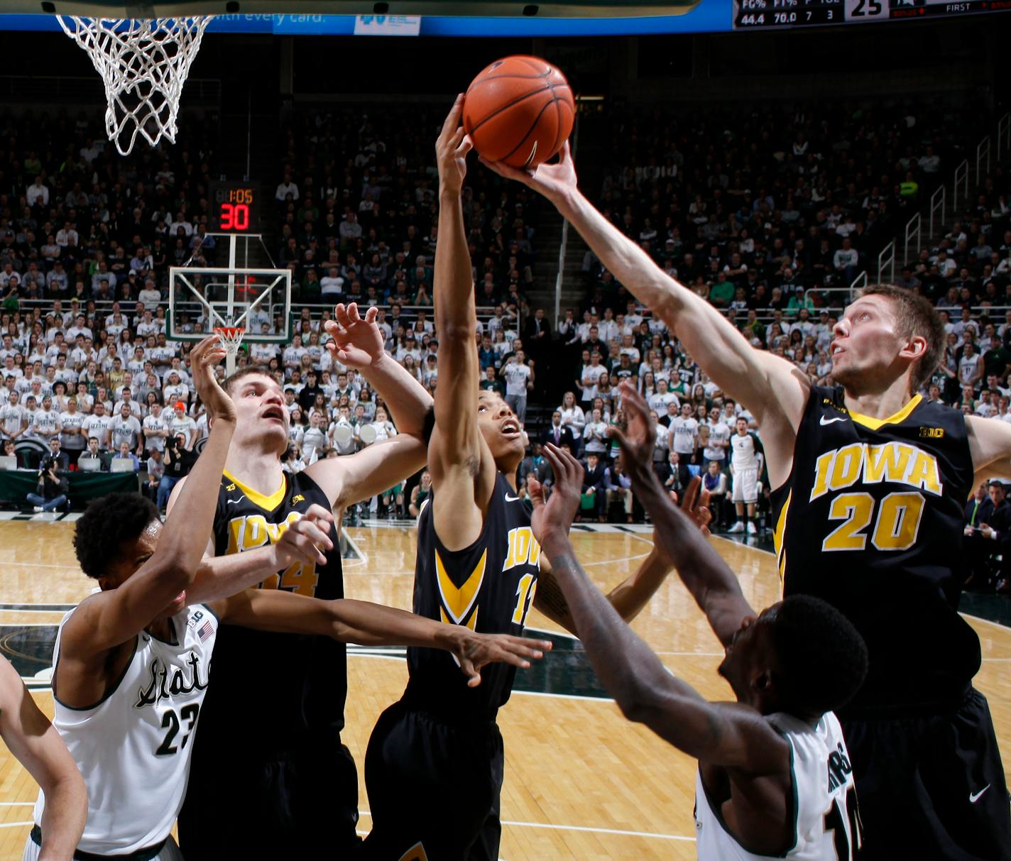 Iowa's Jarrod Uthoff (20), Christian Williams, center, and Adam Woodbury, second from left, and Michigan State's Deyonta Davis (23) and Eron Harris (14) reach for a rebound during the first half of an NCAA college basketball game, Thursday, Jan. 14, 2016, in East Lansing, Mich. (AP Photo/Al Goldis)