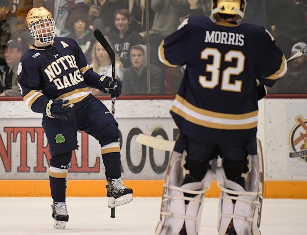 Notre Dame's Jordan Gross celebrated with goaltender Cale Morris (32) after a power play goal by Morris in the first period against the Gophers