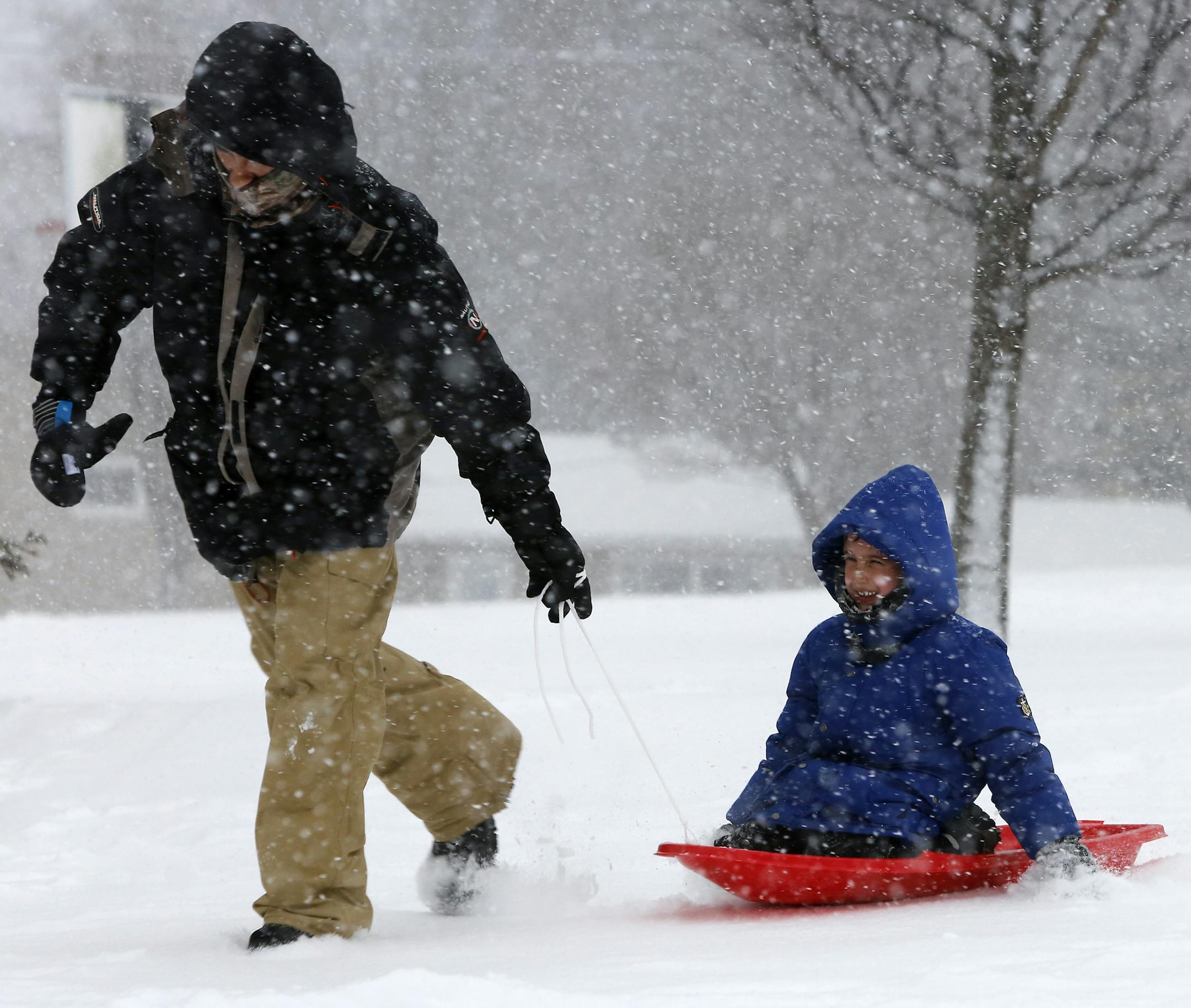 Fabio Carvalho, left, pulls his son, Giovnne, 7, of Rochester, in a sled back to their car after sledding at Judd Park on Monday, Dec. 28, 2015, in Rochester, Minn. (Andrew Link/Rochester Post-Bulletin via AP) ORG XMIT: MIN2015122820433533