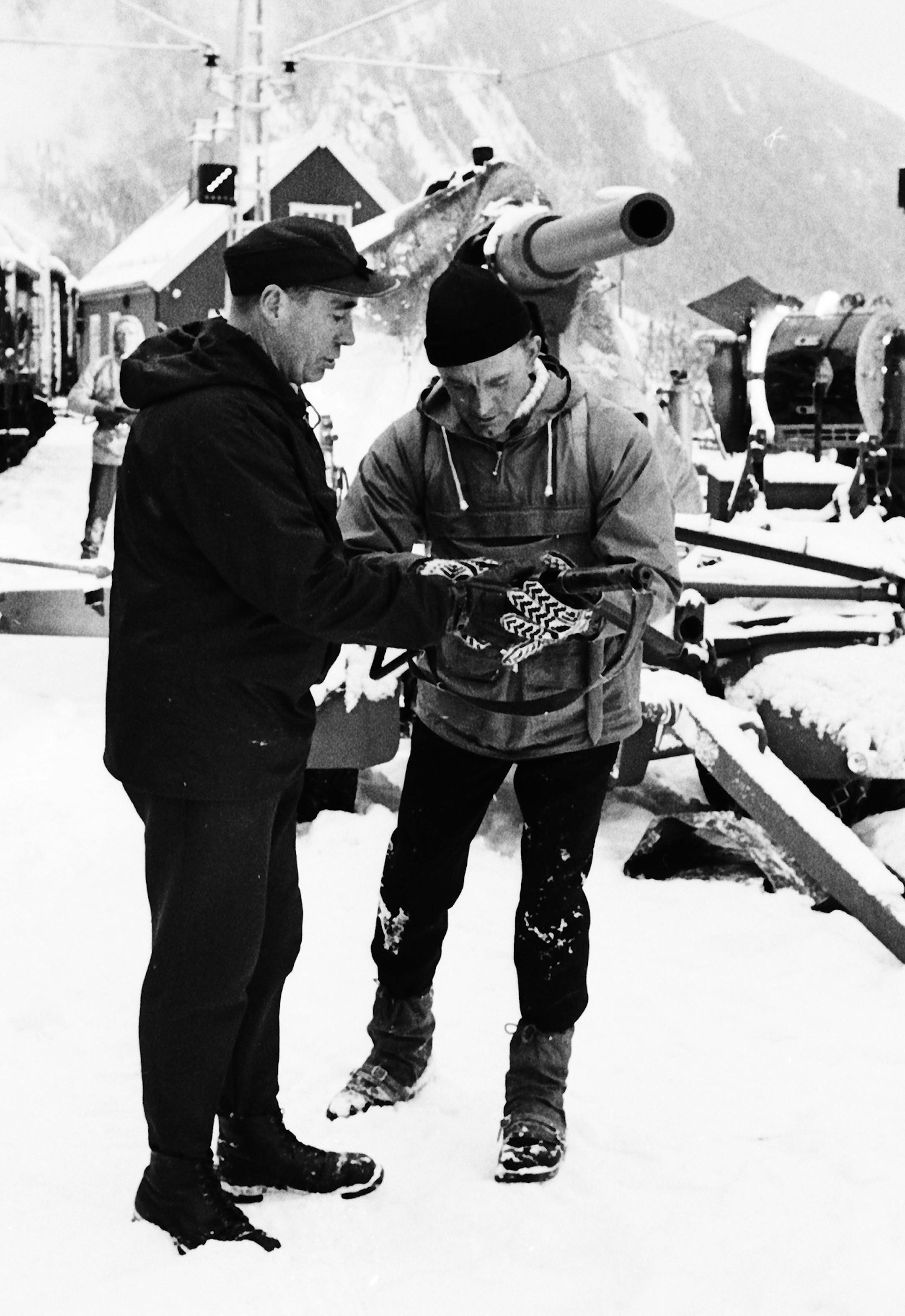 Knut Haukelio, left, one of the original saboyeurs of Hitler's plan to produce an atom bomb in World War II, shows a sten gun to American actor Kirk Douglas, during the filming of the movie "Heroes of Telemark", at Rjukan, Norway, on Feb. " 1965. (AP Photo) ORG XMIT: APHSL70045