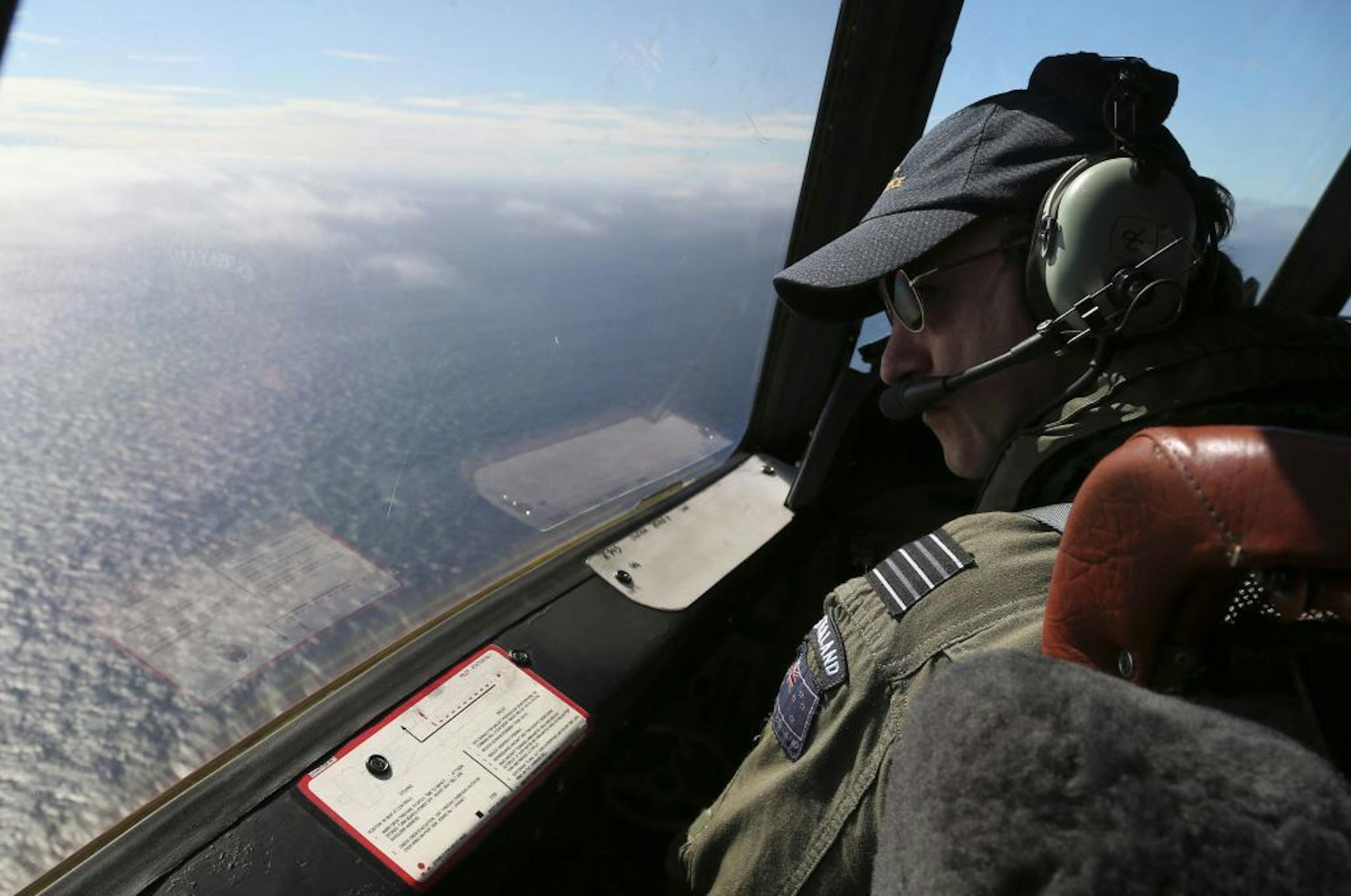 Royal New Zealand Air Force P-3 Orion's captain, Wing Comdr. Rob Shearer, watches out of the window of his aircraft while searching for the missing Malaysia Airlines Flight MH370 in the southern Indian Ocean, Monday, March 31, 2014.