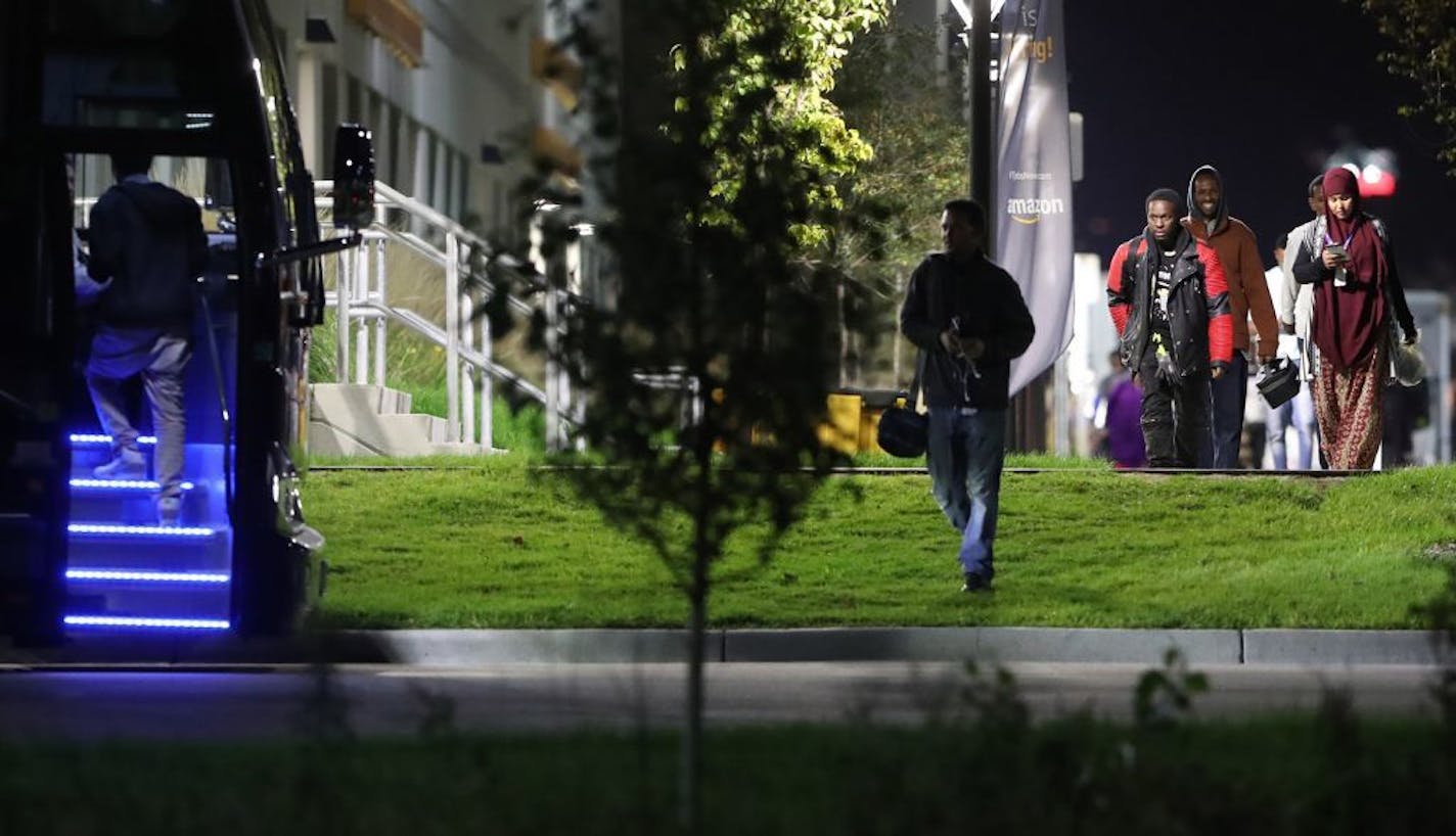 Workers head for an awaiting bus to be transported back to their homes in the Cedar-Riverside neighborhood of Minneapolis after working an overnight shift at Amazon's fulfillment center Wednesday, Oct. 18, 2017, in Shakopee, MN.