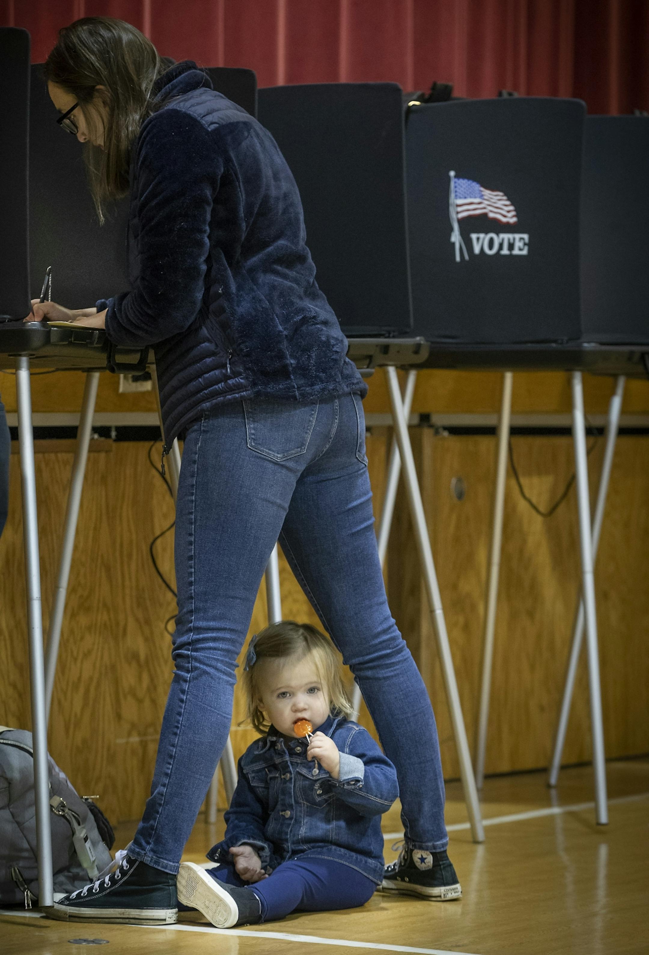 Annie Knier, cq, kept her daughter Zoe, 2, busy with a sucker as she cast her vote at the Mt. Calvary Education Building, Tuesday, November 6, 2018 in Richfield, MN.