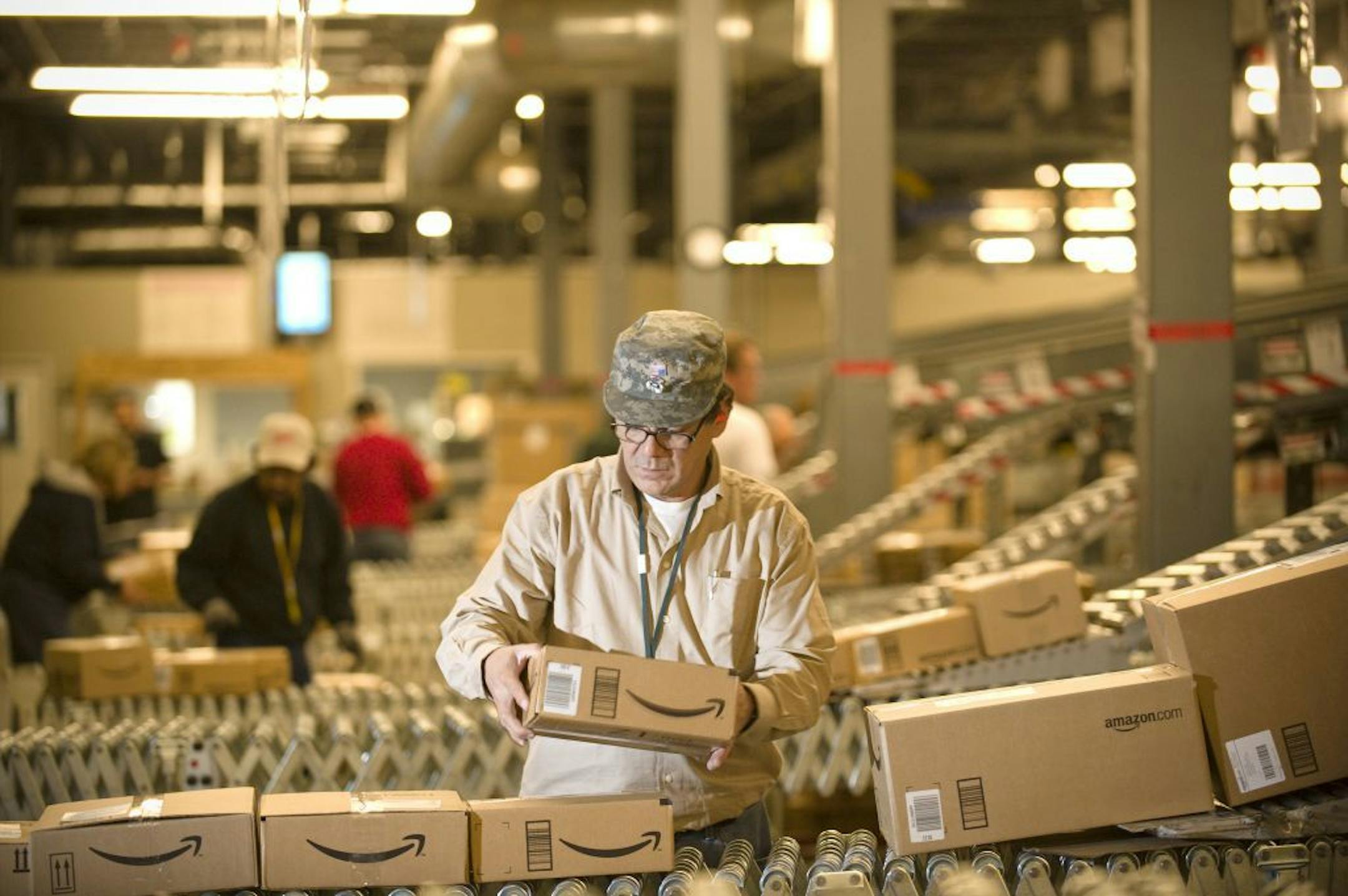 FILE - In this Monday, Dec., 1, 2008, file photo, an Amazon.com employee grabs boxes off the conveyor belt to load in a truck at their Fernley, Nev., warehouse. Cyber Monday, coined in 2005 by a shopping trade group that noticed a spike in online sales on the Monday after Thanksgiving when people returned to their work computers, is the next in a line of days that stores are counting on to jumpstart the holiday shopping season. This year it is expected to be the biggest online shopping day of th