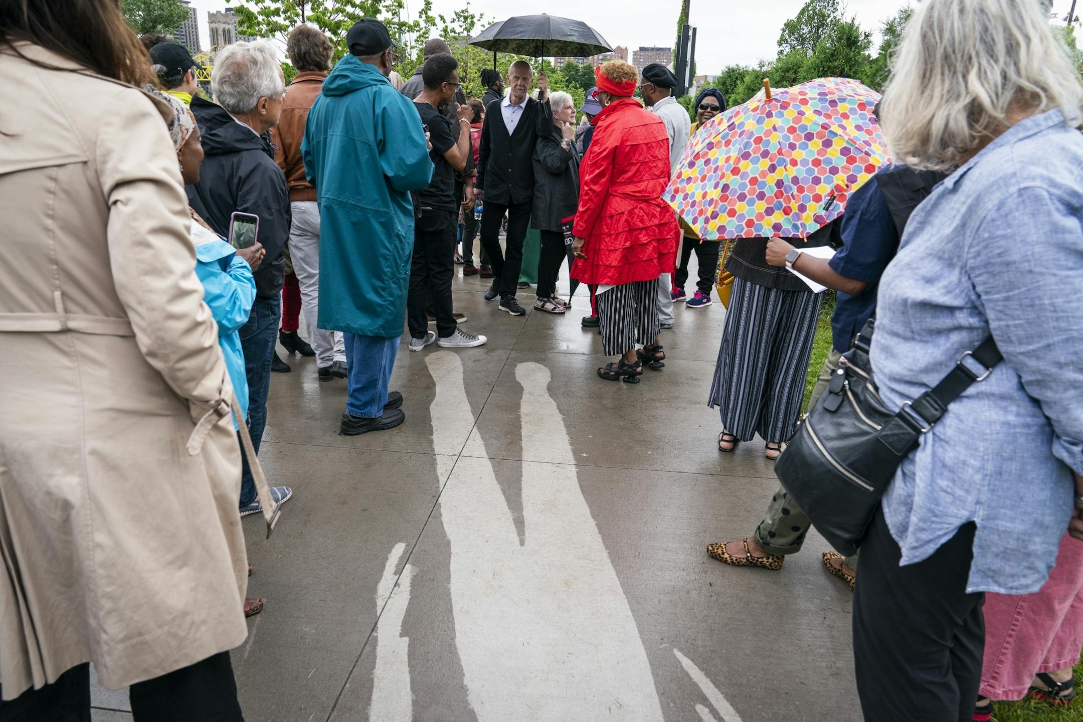 People explore the piece "Kirk Washington, Jr." which only reveals itself when it rains, from the series "Shadows at the Crossroads" during the public unveiling.