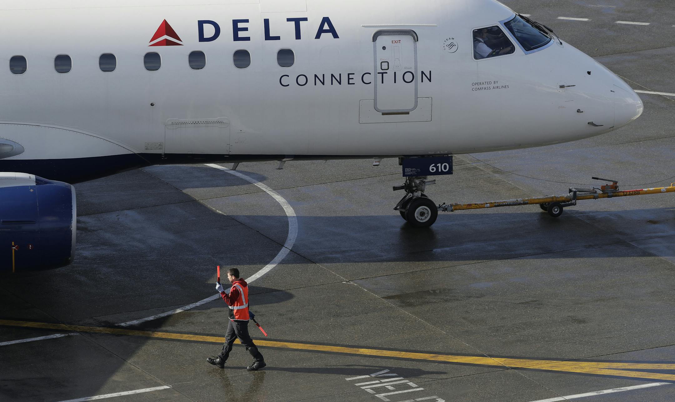 FIE - In this Feb. 5, 2019, file photo a ramp worker guides a Delta Air Lines plane at Seattle-Tacoma International Airport in Seattle. Delta says earnings and revenue will rise in 2020 because of continuing solid demand for air travel and no increase in spending on jet fuel. CEO Ed Bastian says Delta is getting a boost from strong spending by consumers, which he expects to spill into 2020. (AP Photo/Ted S. Warren, File)