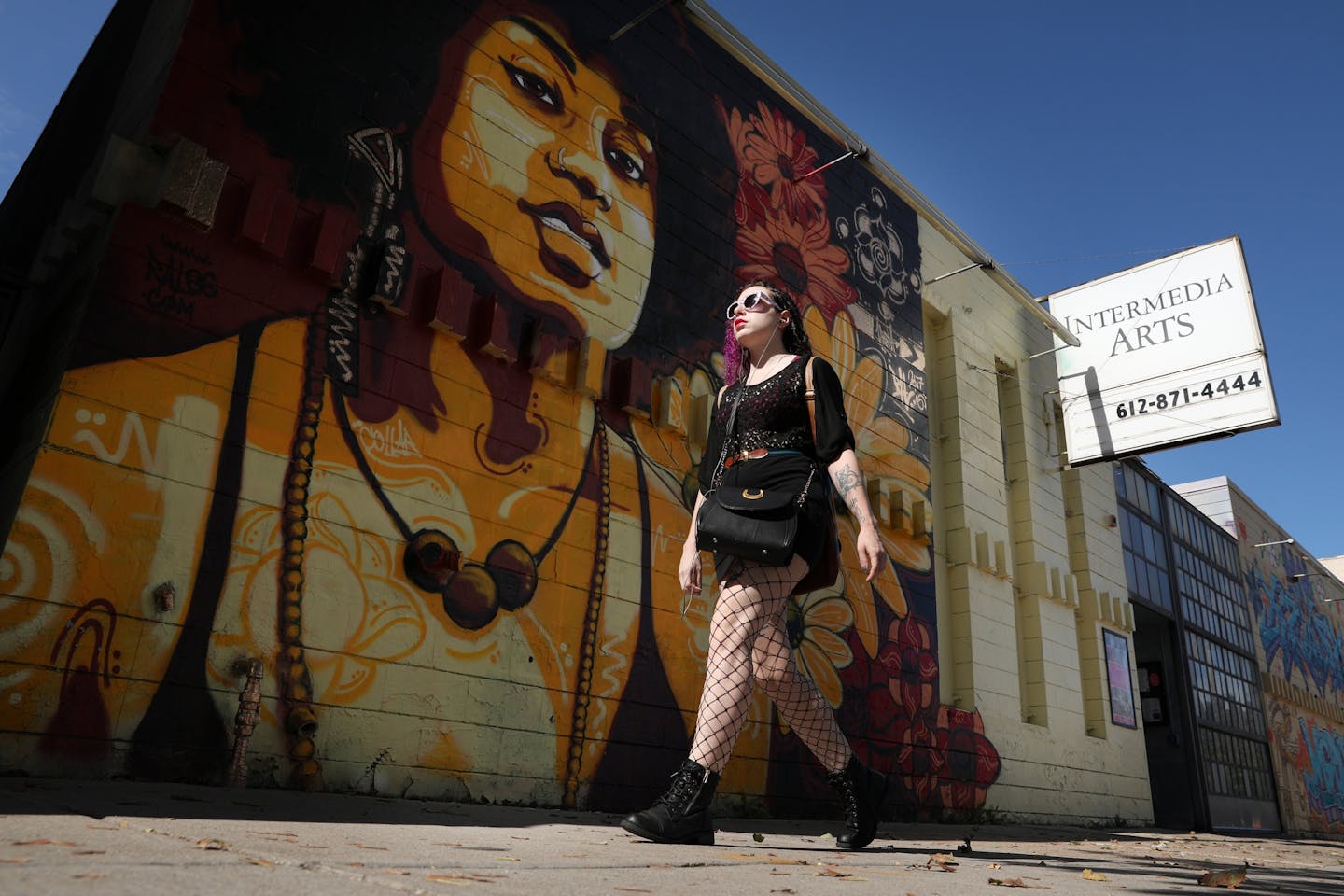 A pedestrian walks past one of the murals that adorns the outside of the Intermedia Arts building Thursday.