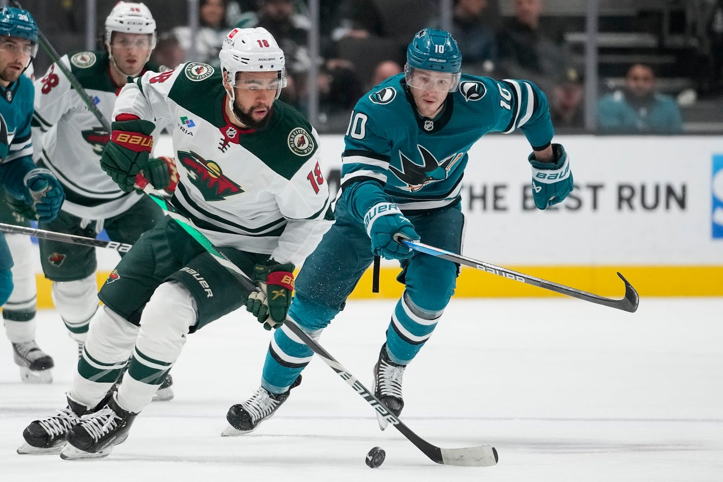 Minnesota Wild left wing Jordan Greenway (18) and San Jose Sharks left wing Evgeny Svechnikov (10) chase the puck during the first period of an NHL hockey game in San Jose, Calif., Thursday, Dec. 22, 2022. (AP Photo/Godofredo A. Vásquez)