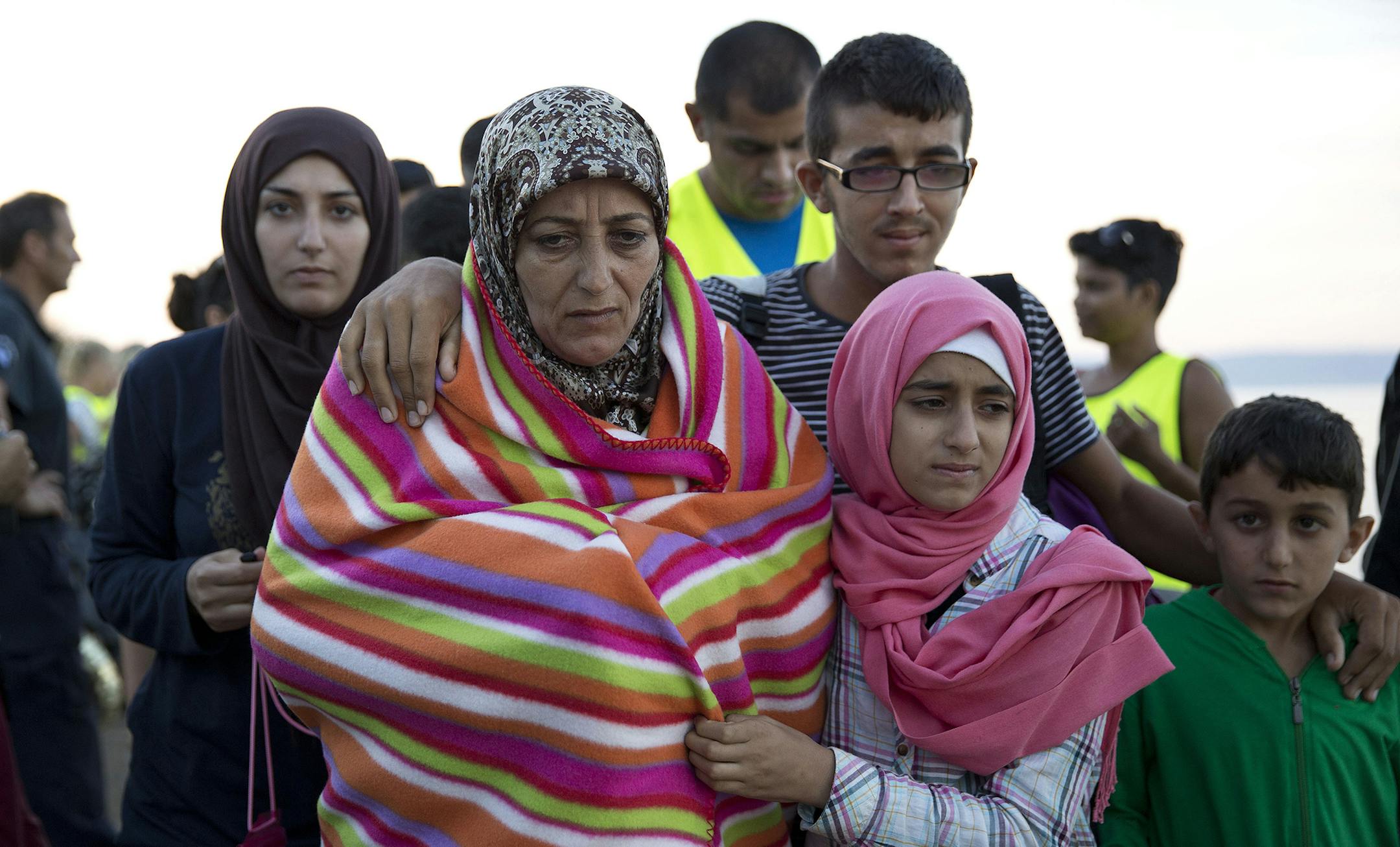 A Syrian family walk after they arrived with other refugees from Turkey to the shores of the Greek island of Lesbos, on a inflatable dinghy, Friday, Sept. 25, 2015. More than 260,000 asylum-seekers have arrived in Greece so far this year, most reaching the country's eastern islands on flimsy rafts or boats from the nearby Turkish coast.(AP Photo/Petros Giannakouris) ORG XMIT: MIN2015092513172757 ORG XMIT: MIN1509251320157394