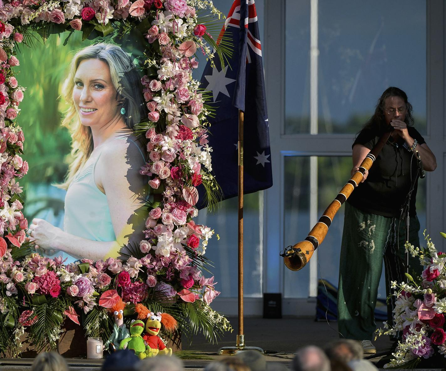 FILE - In this Aug. 11, 2017, file photo, Johanna Morrow plays the didgeridoo during a memorial service for Justine Ruszczyk Damond at Lake Harriet in Minneapolis. Defense attorneys want charges dismissed against a former Minneapolis police officer who shot and killed the Australian woman last year. Attorneys for ex-officer Mohamed Noor argue in motions filed Wednesday, Aug. 15, 2018, that the charges should be dismissed because of prosecutorial misconduct and lack of probable cause. (Aaron Lavi