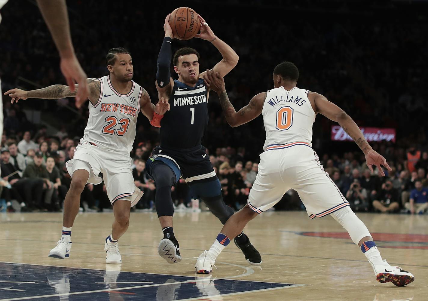 Minnesota Timberwolves guard Tyus Jones (1) drives between New York Knicks guard Trey Burke (23) and forward Troy Williams (0) during the second quarter of an NBA basketball game, Friday, March 23, 2018, in New York. (AP Photo/Julie Jacobson)