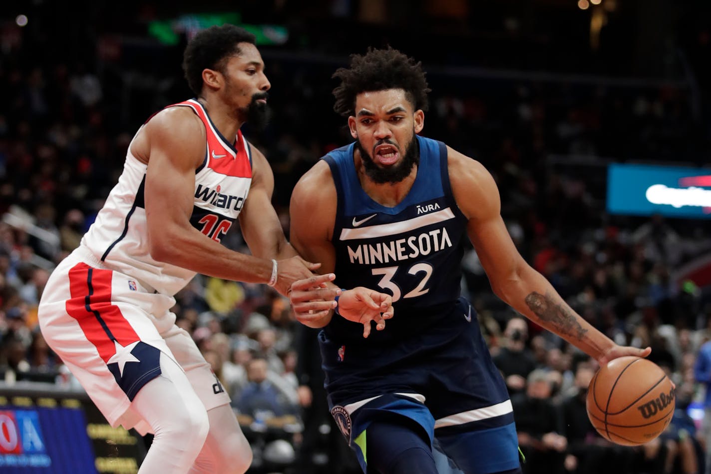 Minnesota Timberwolves' Karl-Anthony Towns (32) moves the ball on Washington Wizards' Spencer Dinwiddie during the second half of an NBA basketball game Wednesday, Dec. 1, 2021, in Washington. (AP Photo/Luis M. Alvarez)