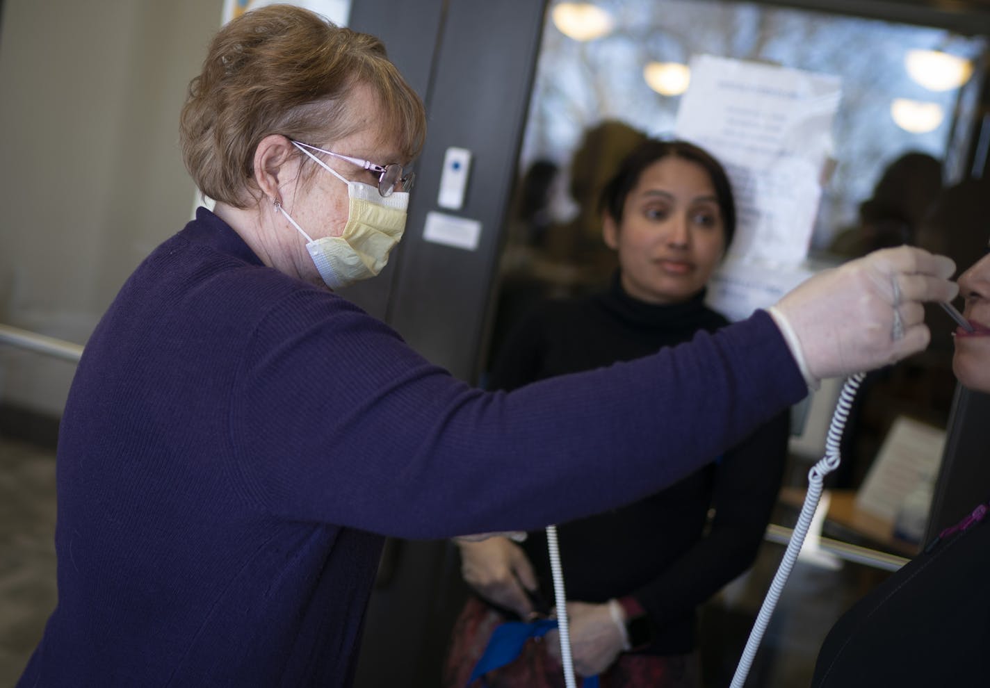 Retired registered nurse Cindy Larson took a patient's temperature when they came to the CARE Clinic for a problem unrelated to COVID-19 in Red Wing, Minn., on Tuesday, March 31, 2020.