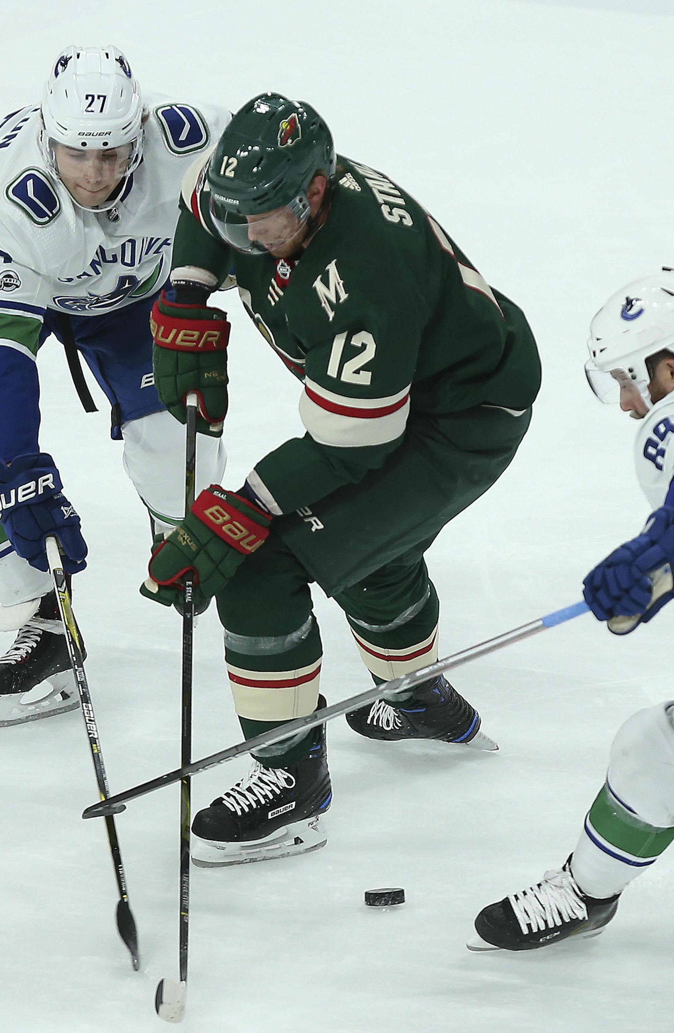 Minnesota Wild's Eric Staal (12) tries to maintain possession of the puck against Vancouver Canucks' Ben Hutton (27) and Sam Gagner (89) in the first period of an NHL hockey game Tuesday, Oct. 24, 2017, in St. Paul, Minn. (AP Photo/Stacy Bengs)