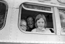 FILE - Children smile from window of a school bus in Springfield, Mass., as court-ordered busing brought Black children and white children together in