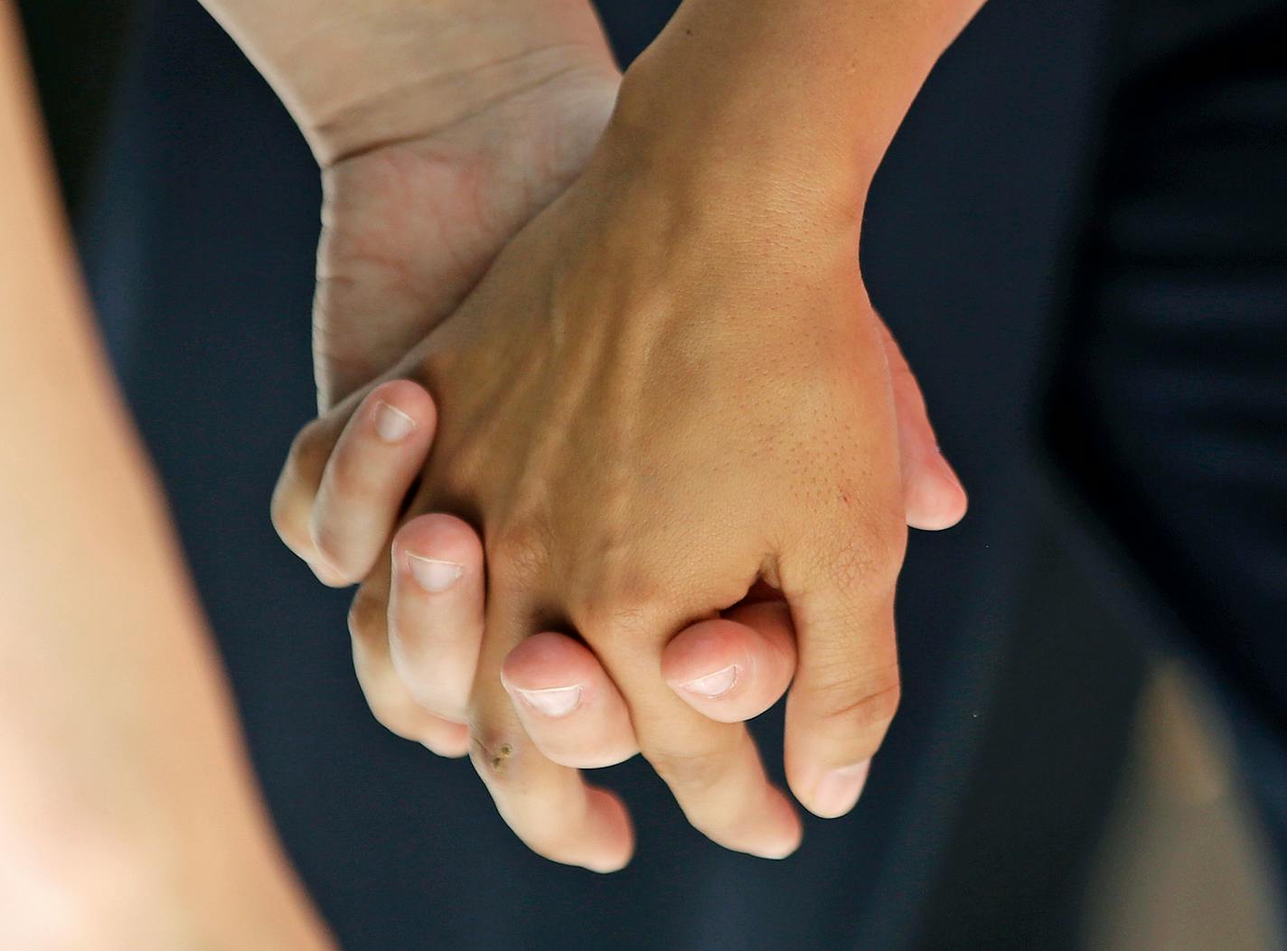 FILE - In this Wednesday, July 15, 2015 file photo, a lesbian couple holds hands in Salt Lake City.