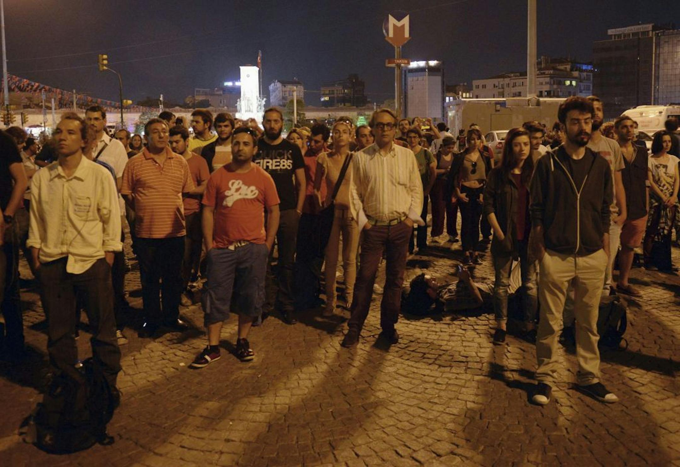 Erdem Gunduz, left, and dozens of people stand silently on Taksim Square in Istanbul, Turkey, early Tuesday, June 18, 2013. After weeks of confrontation with police, sometimes violent, Turkish protesters are using a new form of resistance: standing silently.